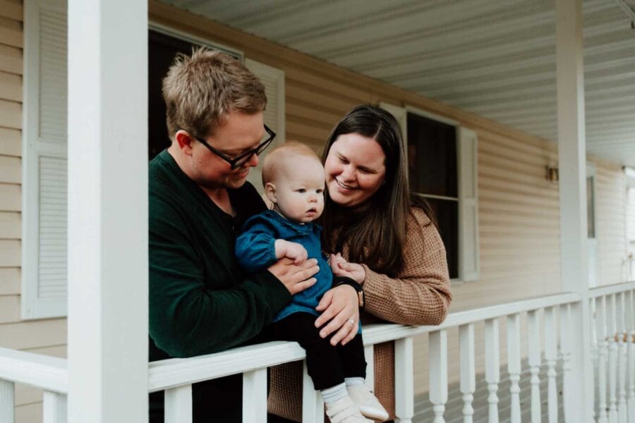 Family enjoying quality time on a porch, holding a baby, representing the concept of home and family life in Minnesota.