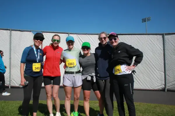 Group of six women posing together at the Maple Grove Lions Half Marathon, wearing race bibs and athletic attire, celebrating their participation in the event.